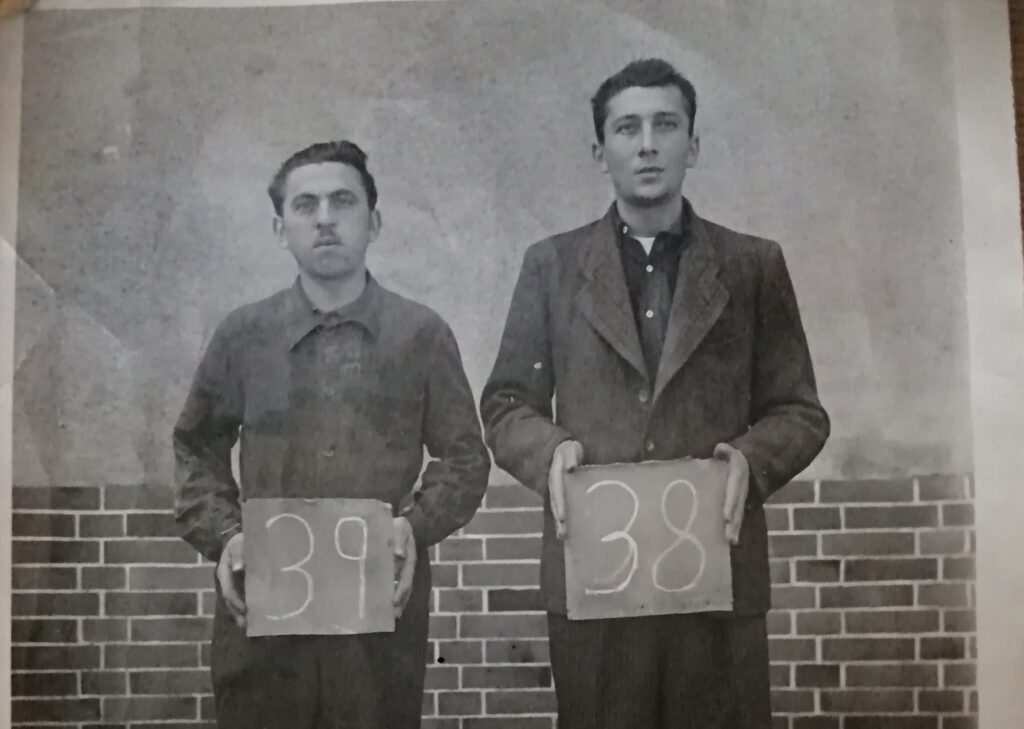 Black and white photograph of two prisoners holding number plaques